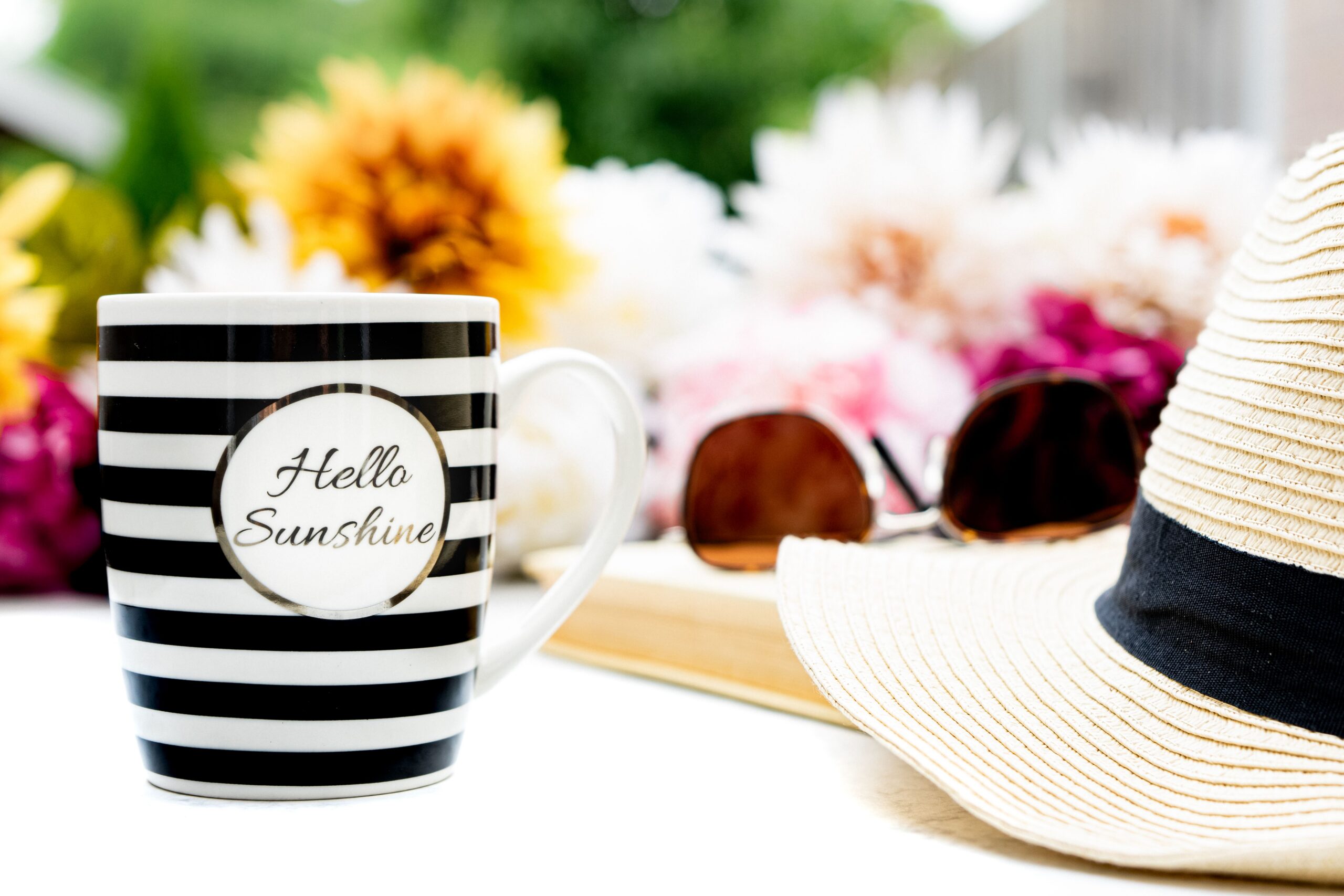 A straw hat, flowers, and a mug
