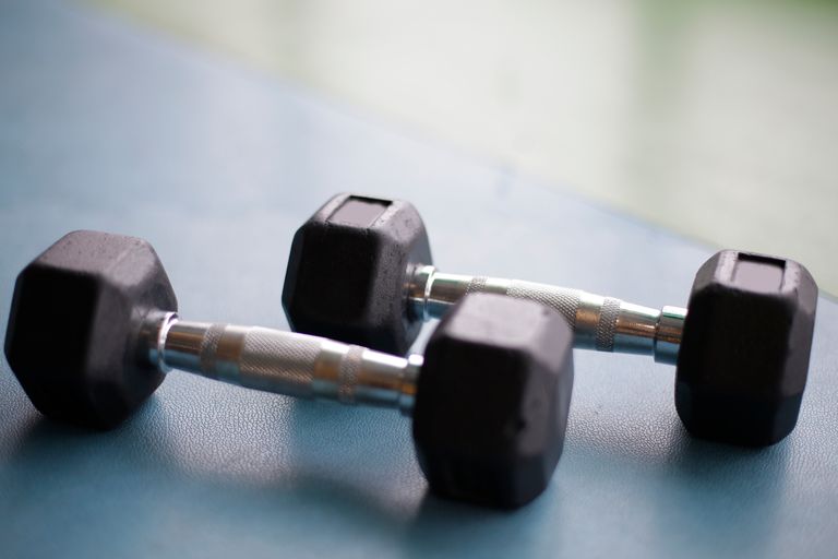 Close-up view of two black hex dumbbells on a gym floor.