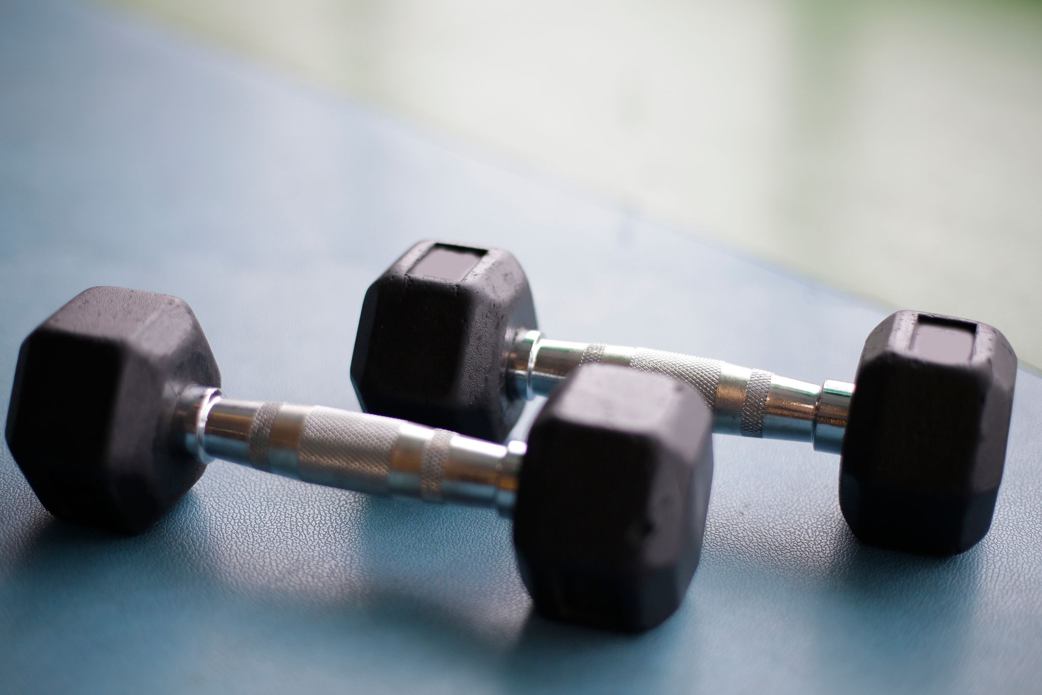 Close-up view of two black hex dumbbells on a gym floor.